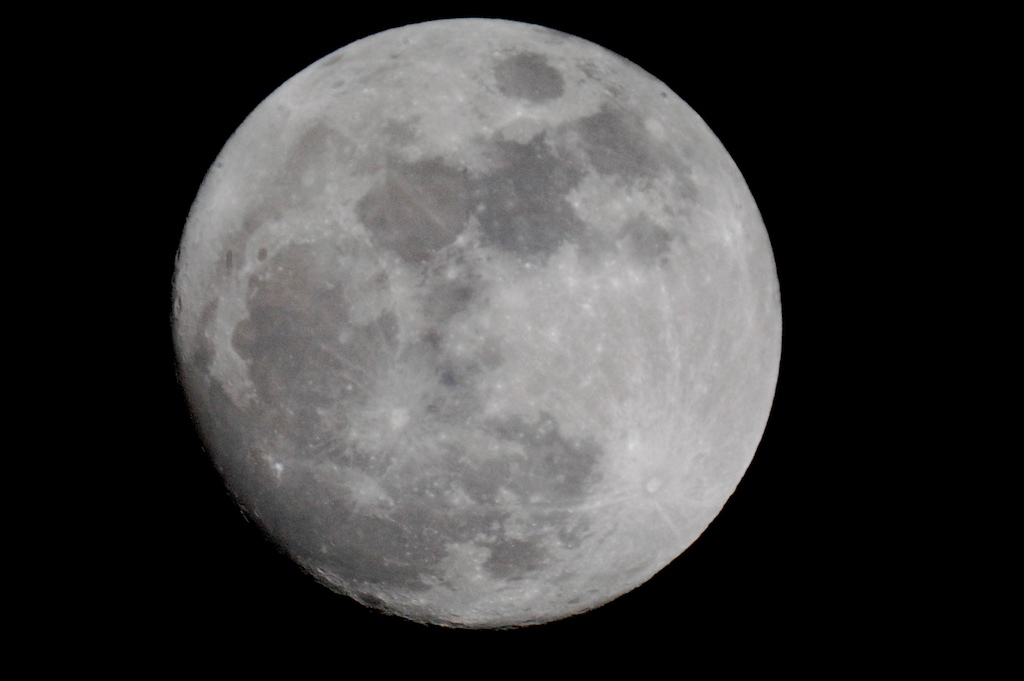 Large black and white image of the Moon at night. 